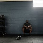 man resting against wall at cross training gym