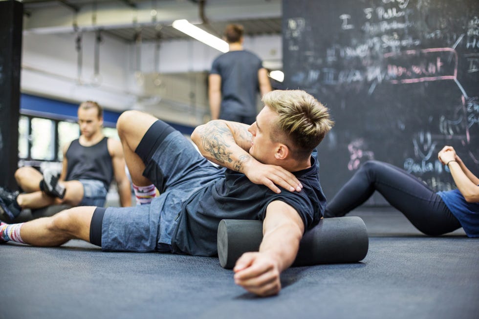 Man rolling on foam roller at health club