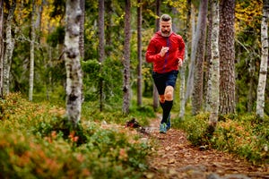 man loopt hard in het bos met trail running schoenen