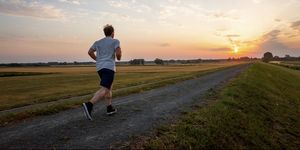 man running in rural landscape at sunset