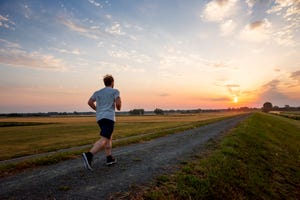 man running in rural landscape at sunset