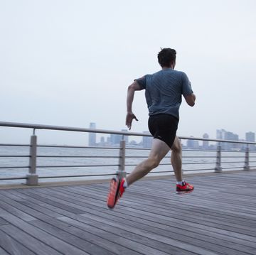 man running l1356 on pier in front of city skyline