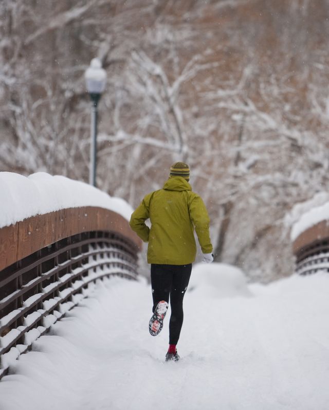 Man running garvalin over snow covered bridge in small town