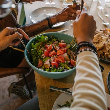 man serving salad from bowl during dinner party