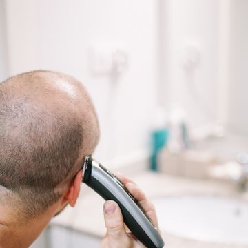 man shaving his head with electric razor in bathroom, lleida, spain