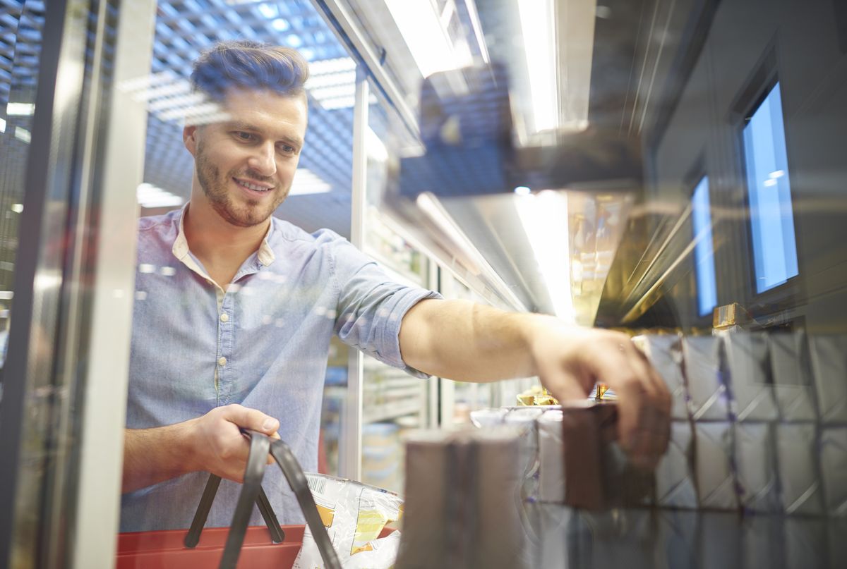 Man shopping for groceries in supermarket freezer