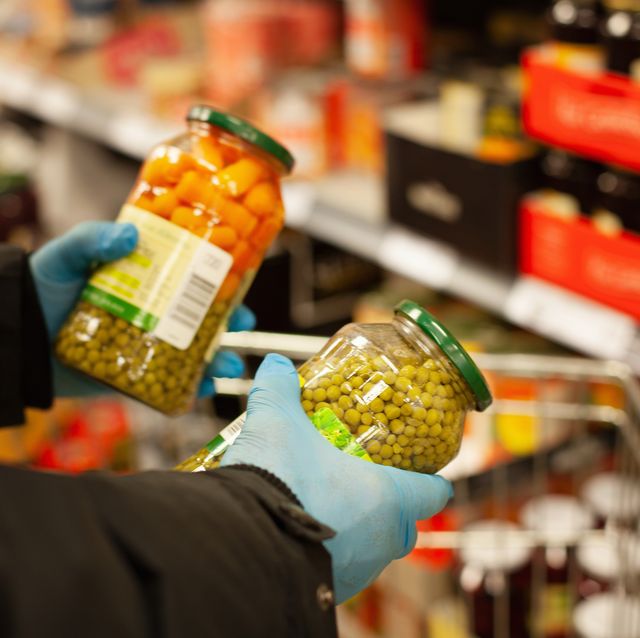 man shopping for preserved vegetables at supermarket, wearing protective gloves