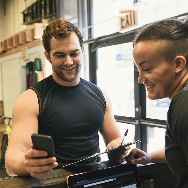 Man showing mobile phone to gym owner
