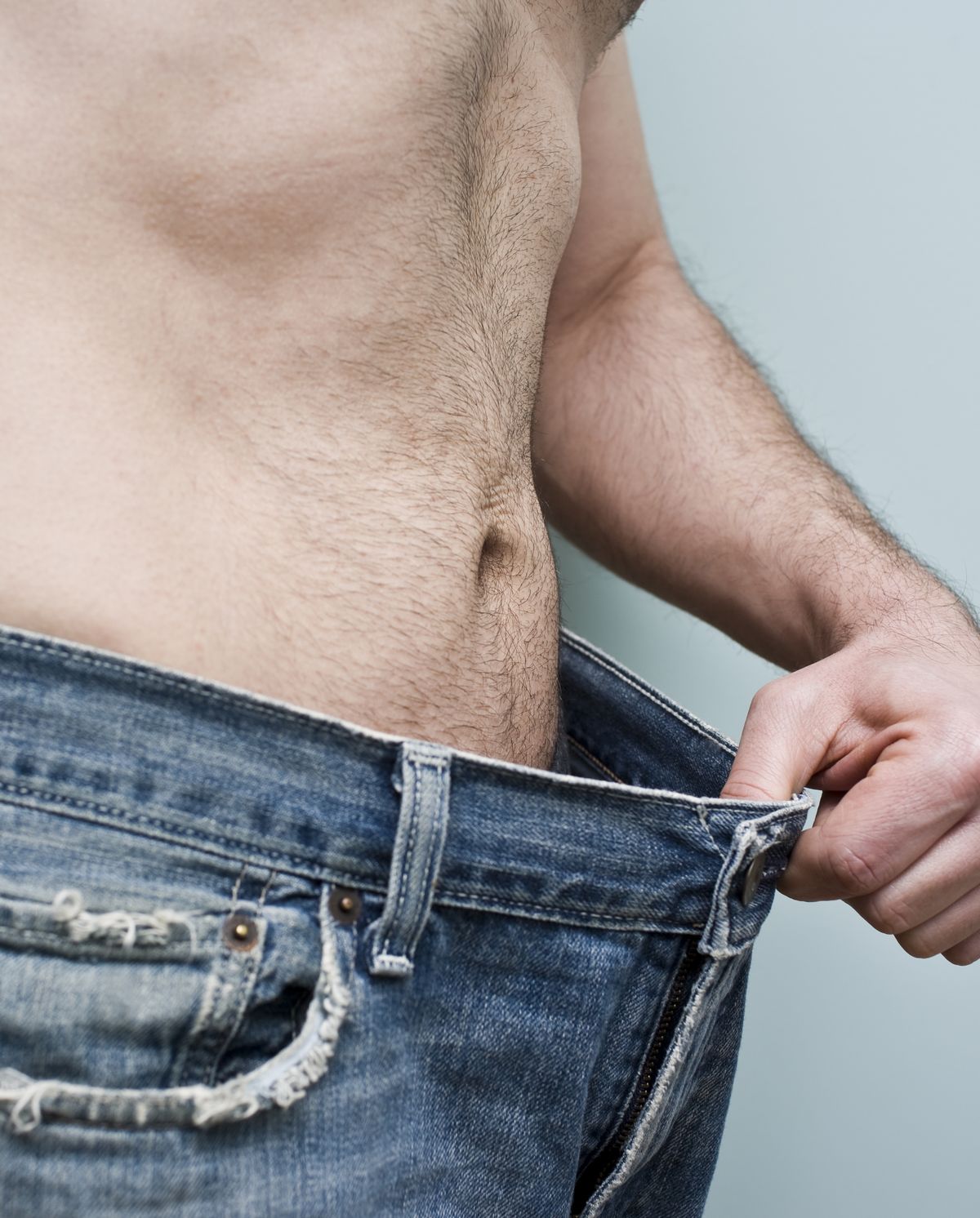 Man showing weight loss by showing his loose pants