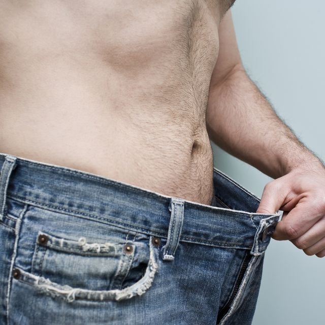 Man showing weight loss by showing his loose pants