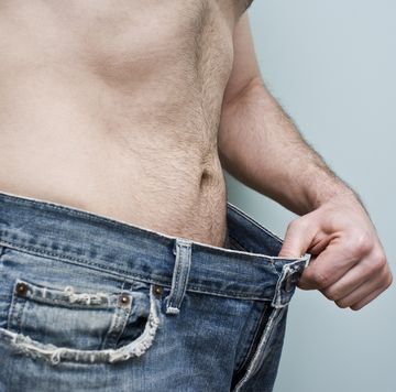 man showing weight loss by showing his loose pants