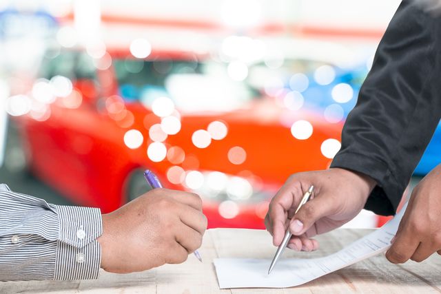 man signing vehicle insurance document or lease paper