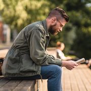 man sitting in a park reading a book