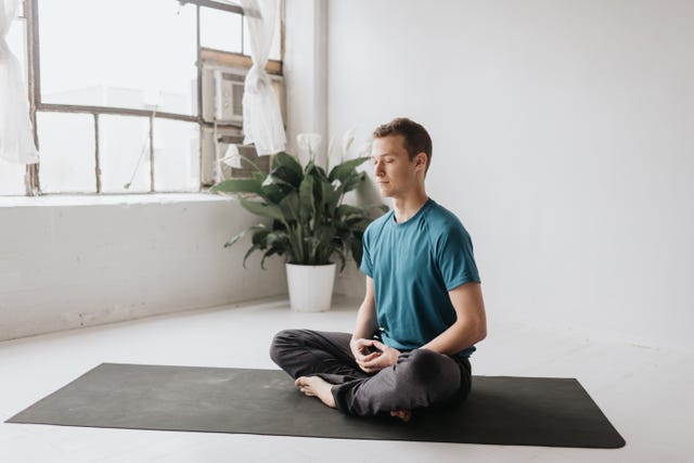 man sitting in lotus pose in yoga studio