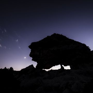 man sitting on a neolithic dolmen enjoying the sunset