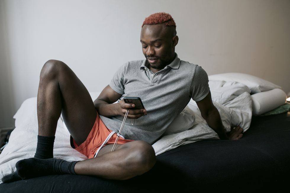 man sitting on bed using gay dating app