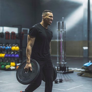 hispanic strong man in gym picking up weights