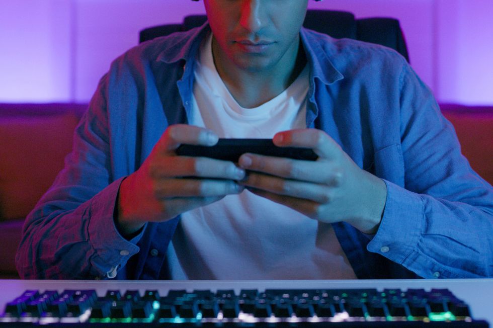 man, smartphone and video game, headphones with live streaming and esports, concentration and gamer playing games technology, competition and focus with male streamer, challenge and gaming room