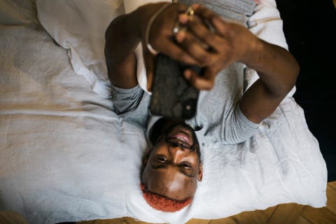 Homme souriant allongé sur le lit Messagerie à l'aide d'un smartphone homme souriant tout en étant allongé sur le lit, messagerie à l'aide d'un smartphone
