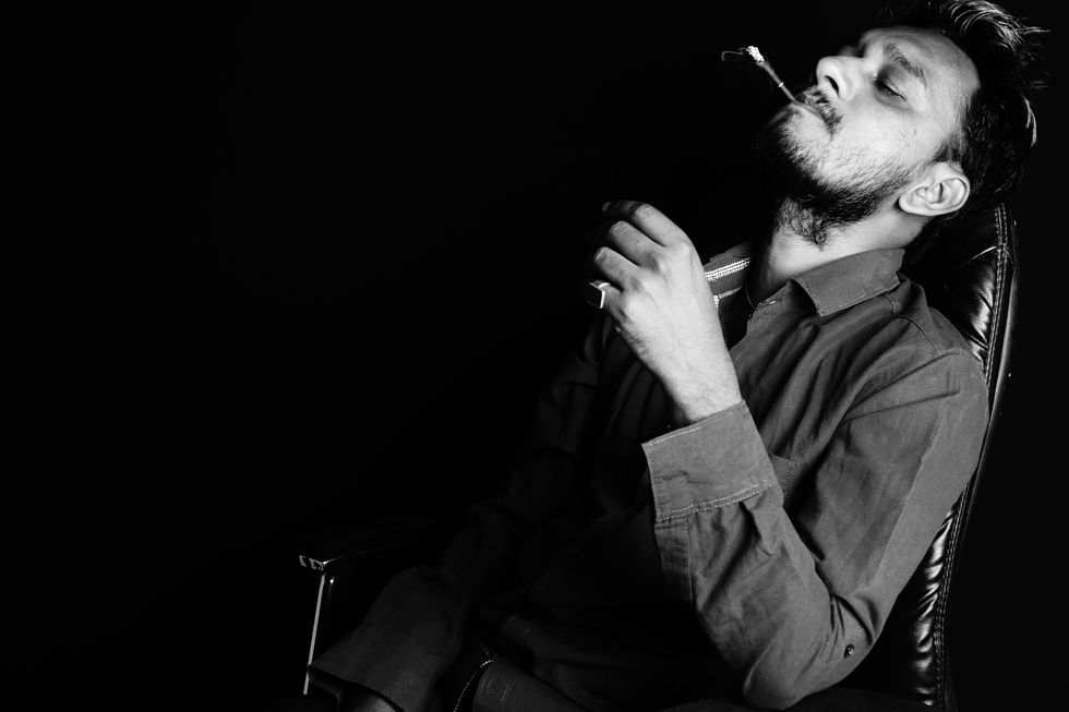 man smoking cigarette against black background