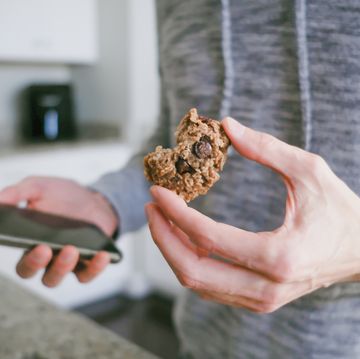 man snacks on cookie while looking at his smart phone