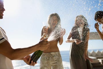 un hombre abriendo una botella de champan con amigos