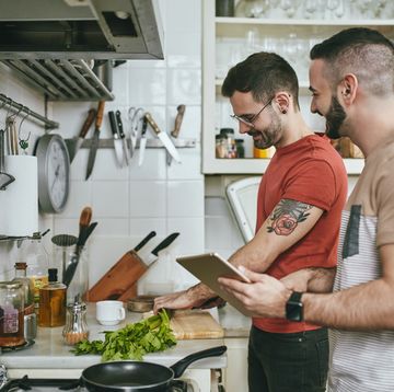 man standing by boyfriend preparing food at home