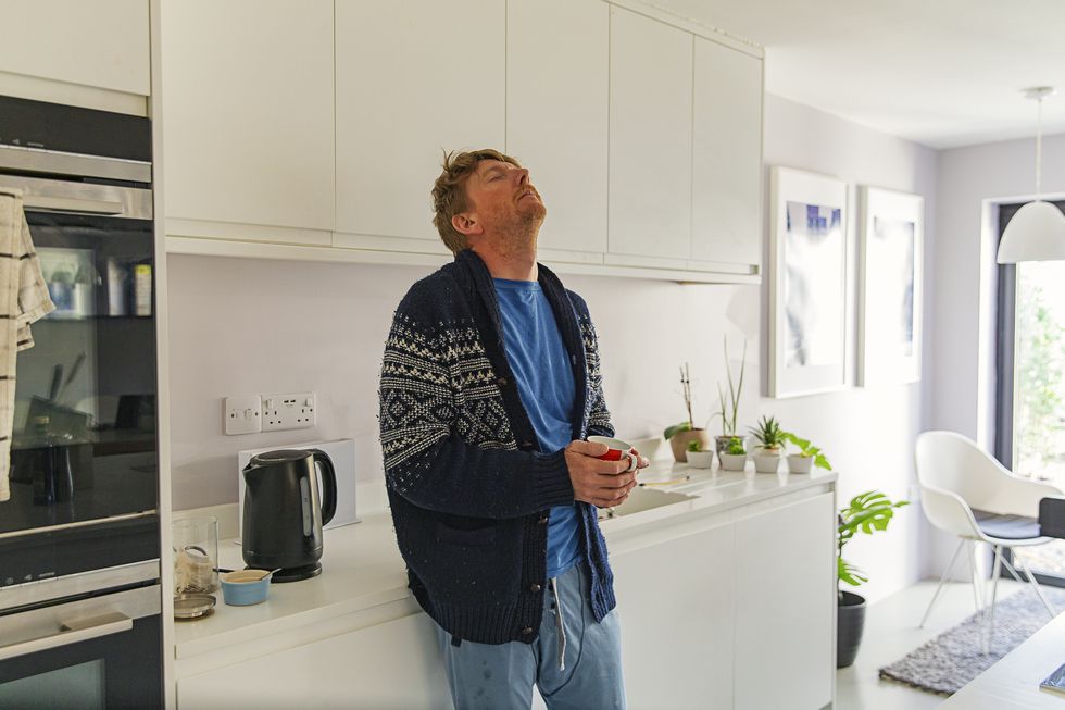 man struggling with flu like symptoms in the kitchen