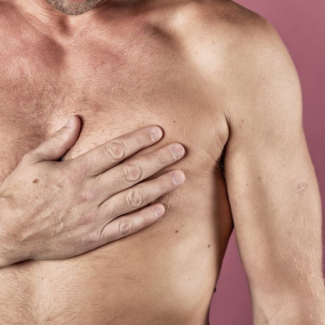 man suffering from chest pain, having heart attack or painful cramps, pressing on chest with painful expression on pink backgound severe heartache