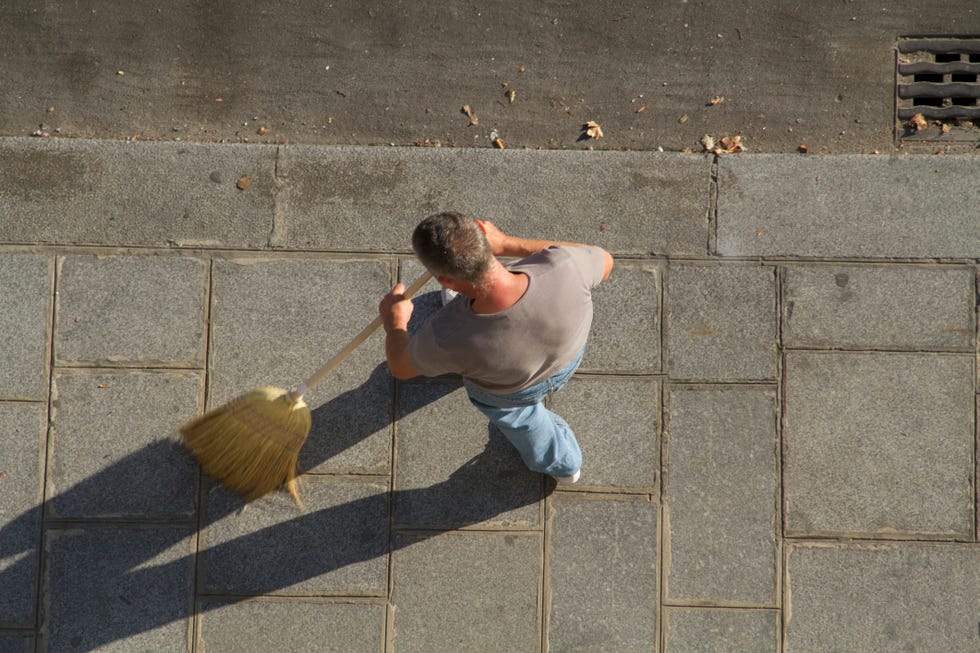 man sweeping the sidewalk with broom