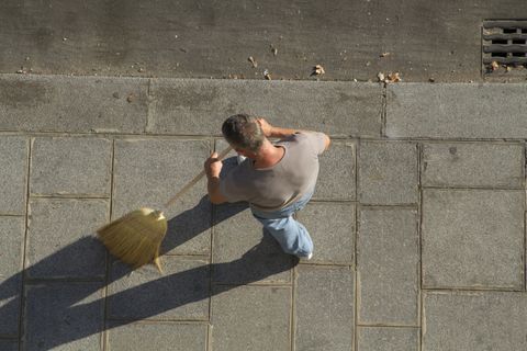 man sweeping the sidewalk with broom