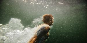 man swimming toward surface of lake