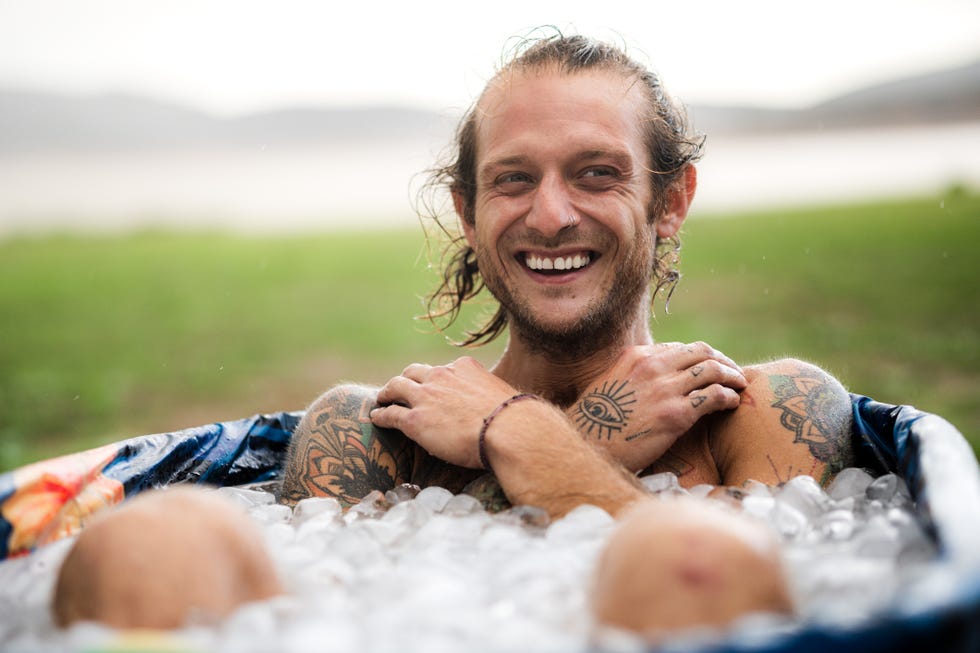 man taking an ice bath in the middle of a field