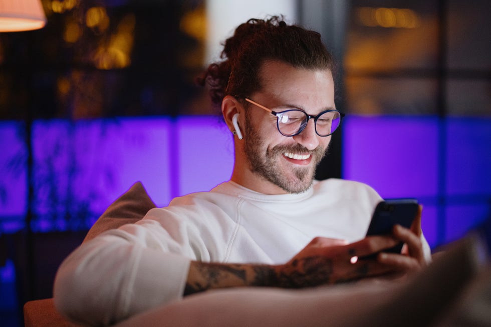 man texting on mobile phone while relaxing at home late at night