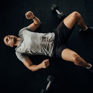 man tired of training with dumbbells lying on the floor in gym