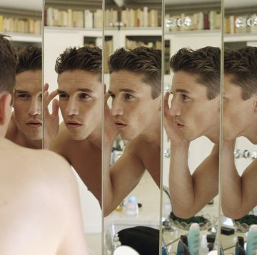 man touching eyebrow, focus on multiple reflections in mirrors
