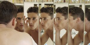 man touching eyebrow, focus on multiple reflections in mirrors