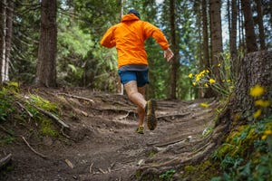 man trail running in the forest, jumping on rough terrain