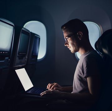 man traveling by airplane young passenger using laptop during night flight