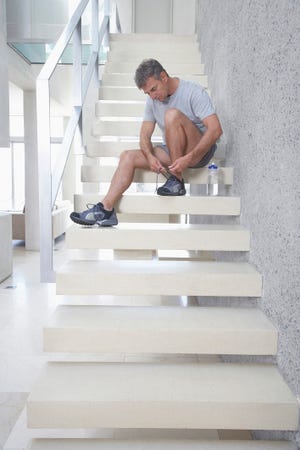 Man Tying His Shoes on Stairway