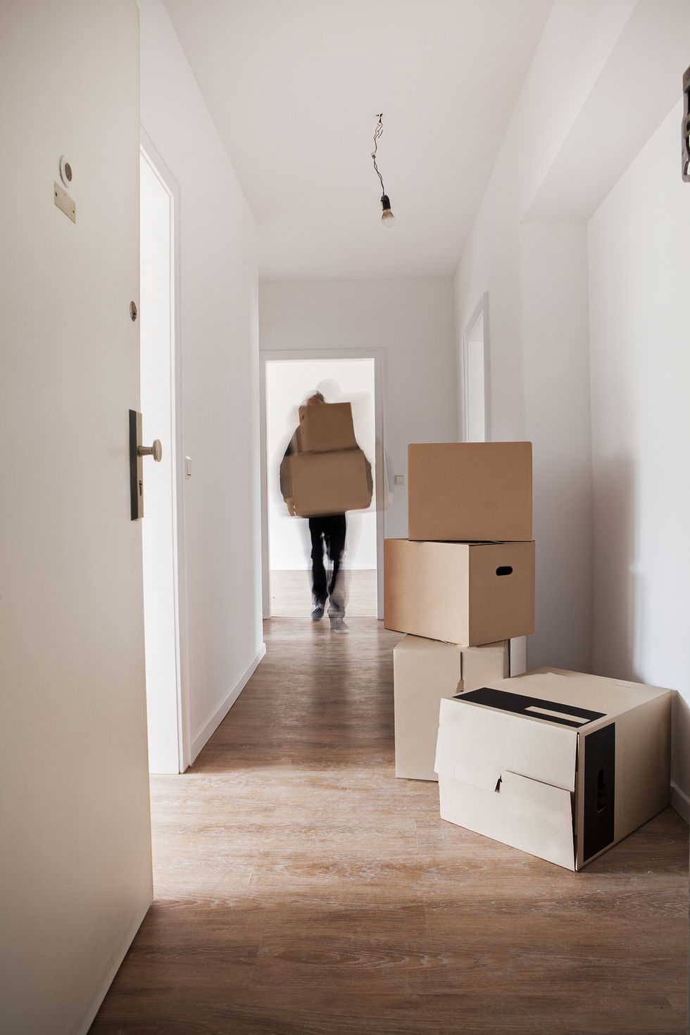 Man unloading cardboard boxes in the hallway of a new house