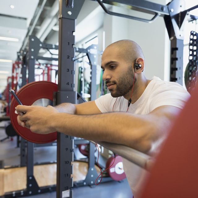 Man using cell phone at barbell in gym