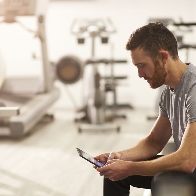 man using digital tablet in gym after exercising