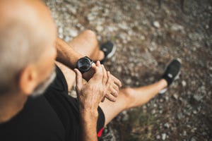 man using fitness tracker or smart watch before run training outdoors closeup photo with dark background