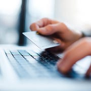 man using laptop and holding credit card, close up