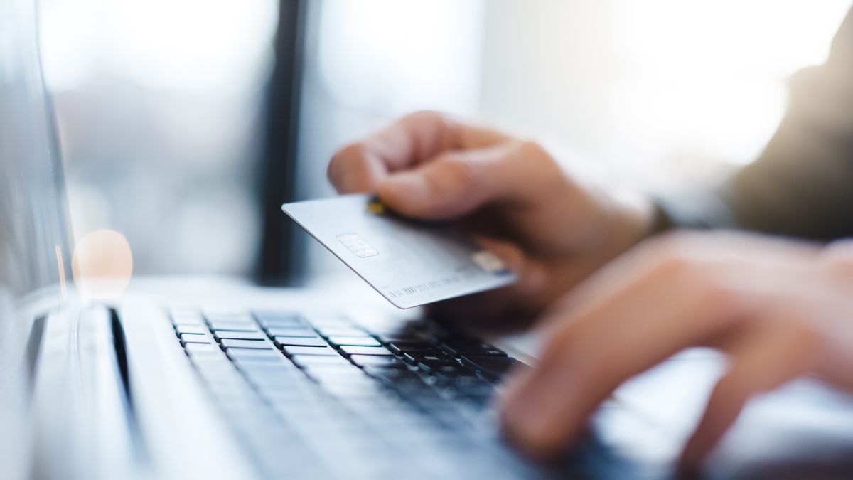man using laptop and holding credit card, close up