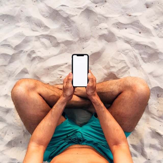 Man using smartphone at the beach, personal perspective directly above view