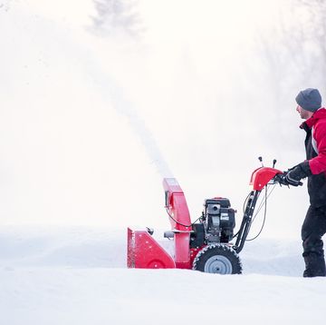 man using snow blower on winter day