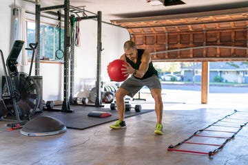 man using weighted exercise ball while doing hiit workout in home gym