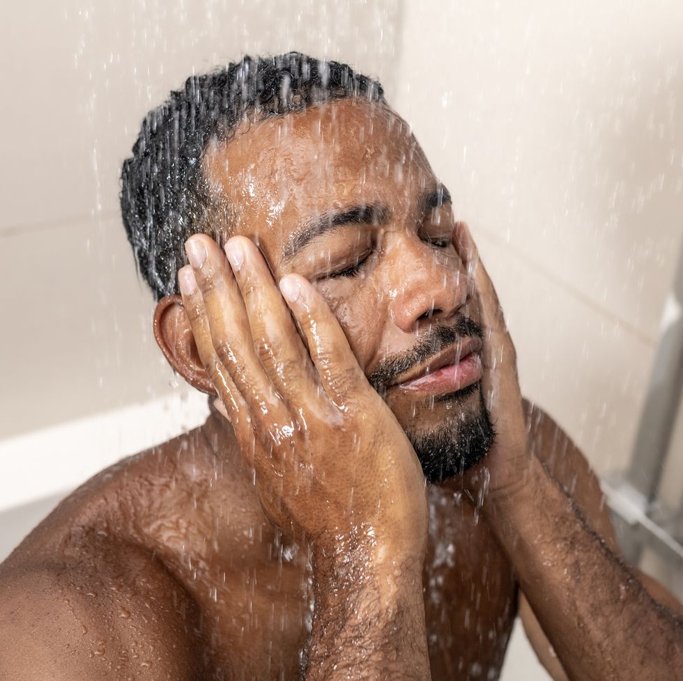 man washing face in shower
